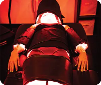 Client lying under full-body red light pads